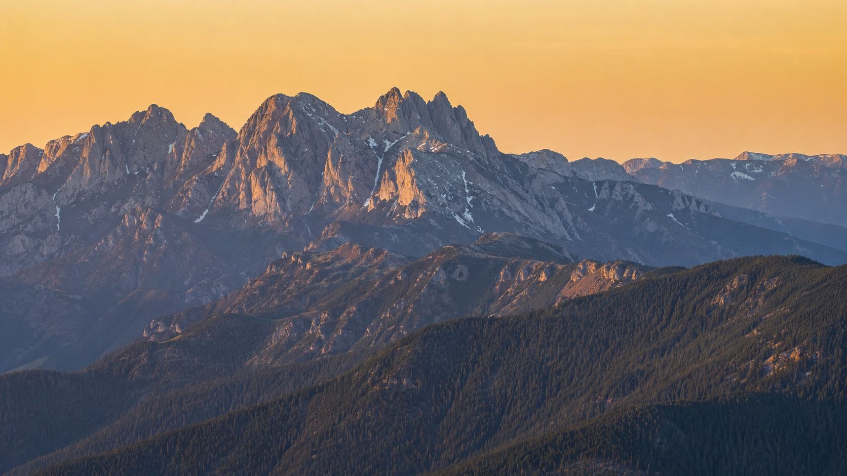 The Bucegi ridgeline above the Văleni hills, the shape echoed in the TAIGA mark.